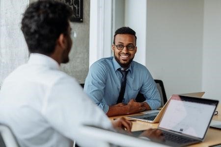 Dos hombres sonriendo mientras tienen una reunión