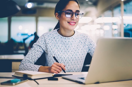 Una mujer estudiando frente a su computadora portátil