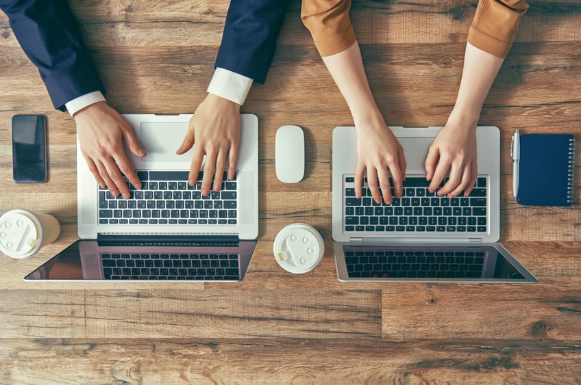 Dos personas trabajando frente a sus dos laptops