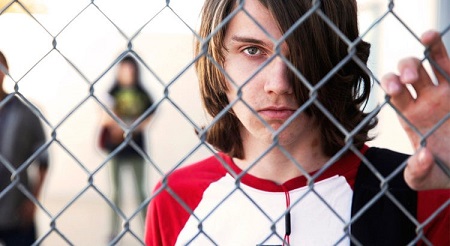 Joven detrás de una reja, con mirada profunda